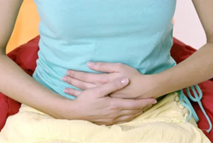 Woman pressing her <a tabindex='0' class='popover-dismiss' href='/glossary/a#abdomen' data-target-type='glossary' data-target-url='/glossary/a#abdomen' data-bs-toggle='popover' data-bs-trigger='focus' title='abdomen' data-bs-content='1486' >abdomen</a> to relieve cramps due to premenstrual syndrome.